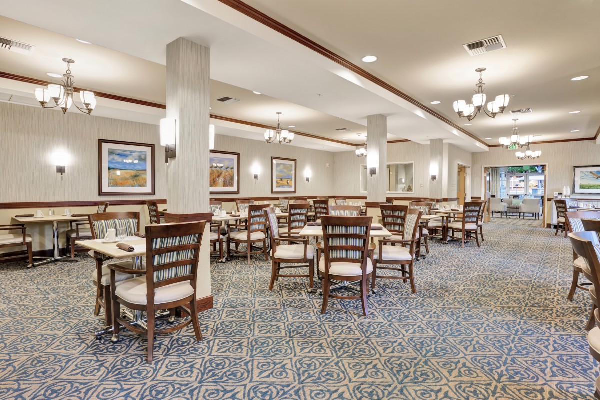 A spacious dining area with neatly arranged tables and chairs, featuring elegant decor and soft lighting.