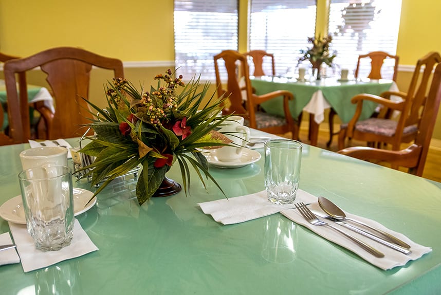 A well-decorated dining table with plants and neatly arranged utensils in a restaurant setting.
