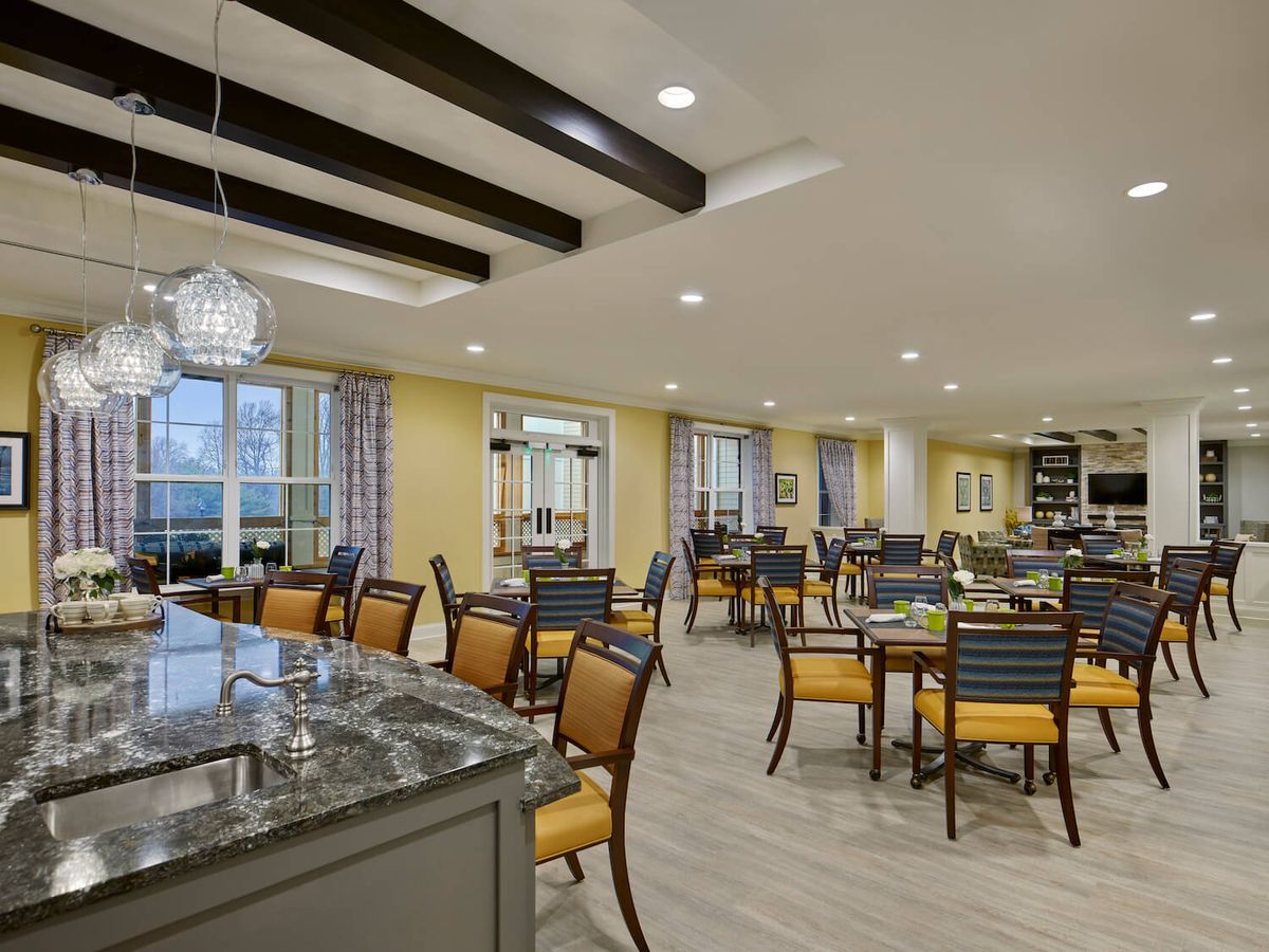 A modern dining area with neatly arranged tables and chairs, featuring elegant lighting and decor.