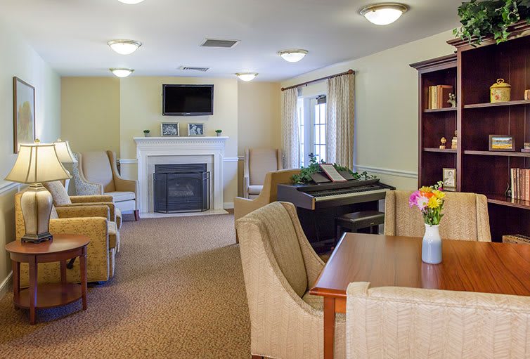 A cozy living room featuring a fireplace, television, and a piano, with comfortable seating and stylish decor.