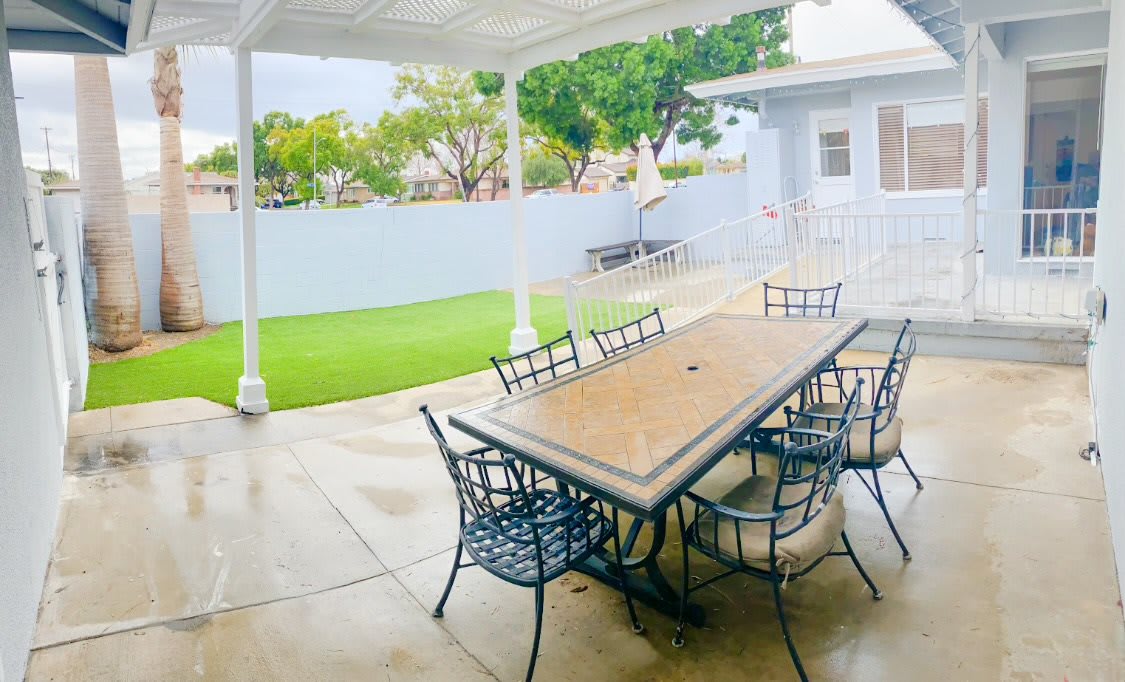 A cozy outdoor patio with a large table and chairs overlooking a small garden.