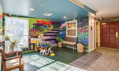 A colorful indoor space featuring a mural of flowers and a bench with dog sculptures.
