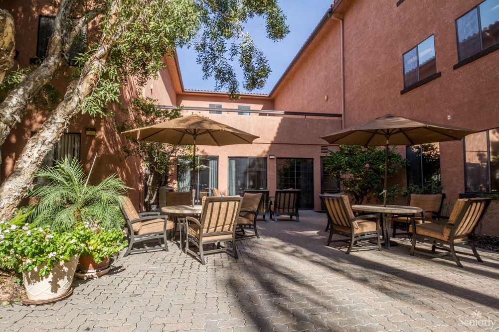 A tranquil courtyard with tables and chairs under large umbrellas on a sunny day.