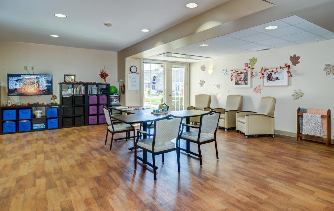 A cozy living area with chairs and a table, adorned with decorations and large windows.