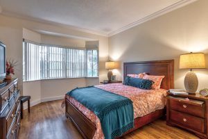 A cozy bedroom with a large bed, wooden furniture, and soft lighting.