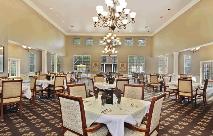 An elegant dining room with chandeliers and neatly arranged tables and chairs.