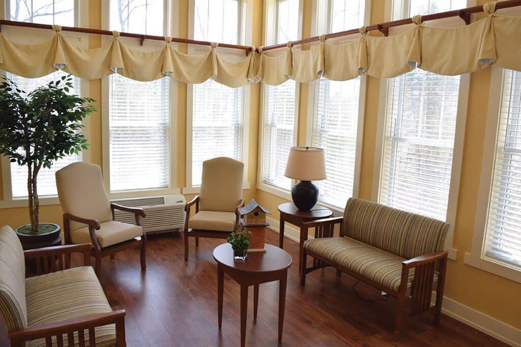 A cozy seating area with abundant natural light, featuring comfortable chairs, a sofa, and a small table.