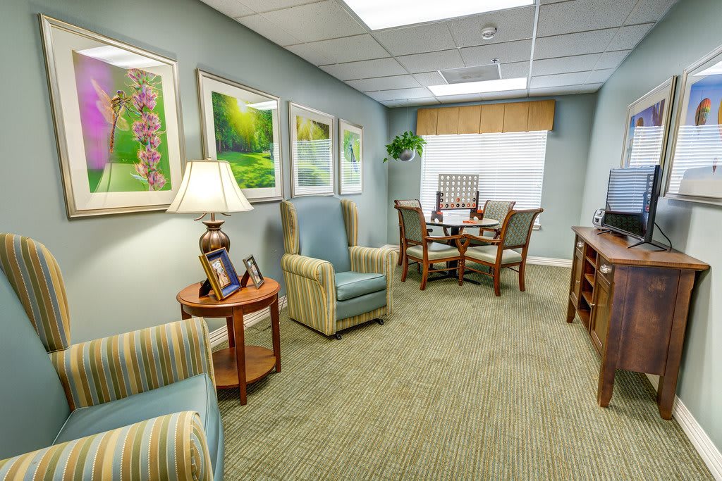 A cozy office waiting room with comfortable chairs, a small table, and decorative artwork on the walls.