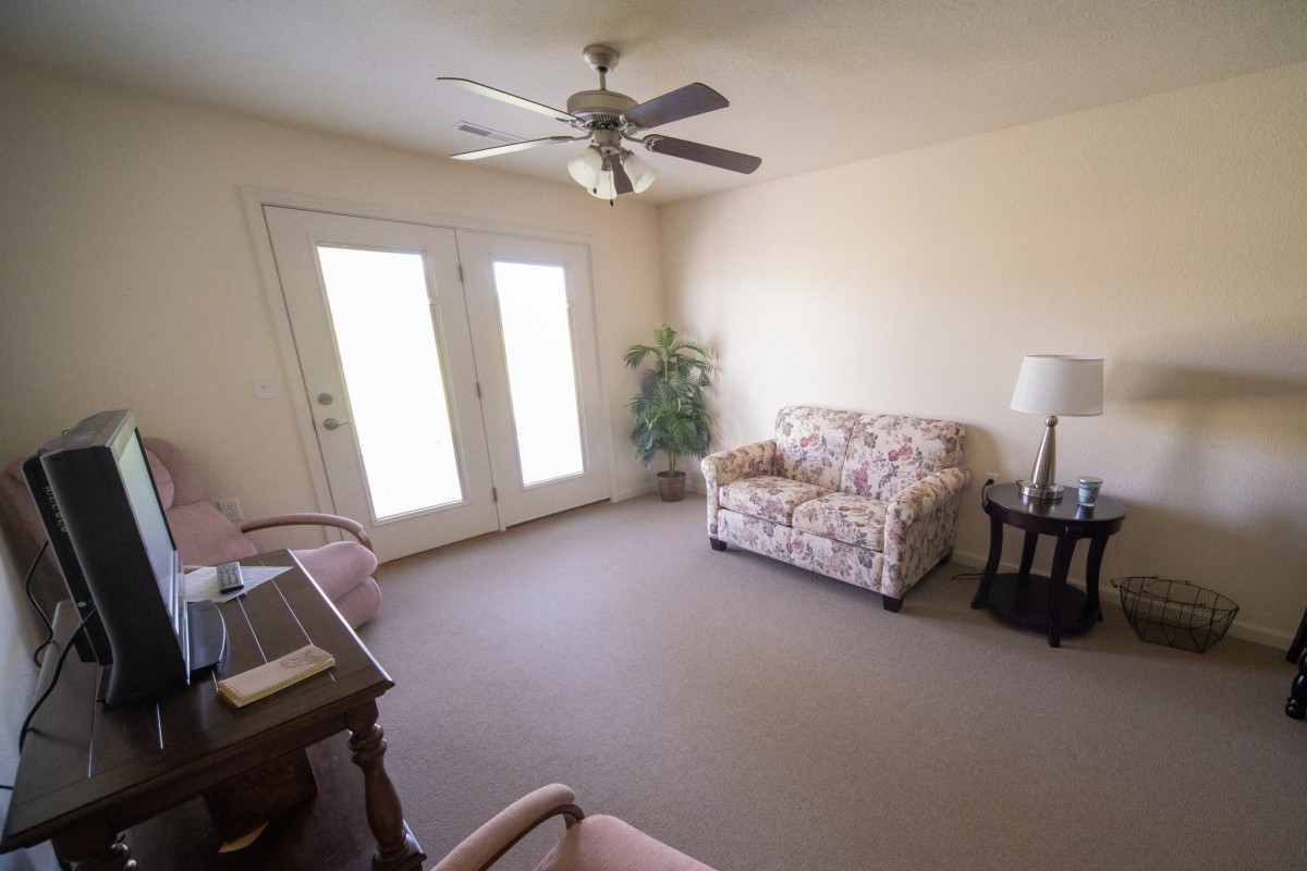 A cozy living room with a sofa, armchair, and ceiling fan.