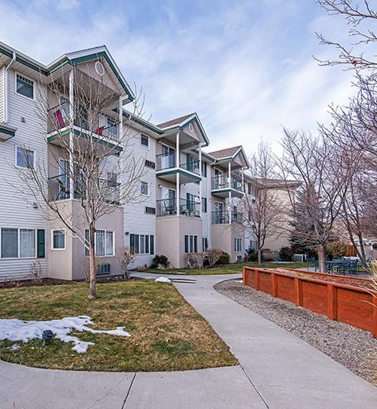 A residential apartment building with a tidy sidewalk and bare winter trees.