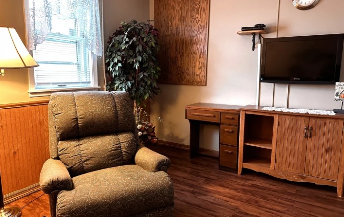 A cozy living room corner with an armchair, desk, and TV.