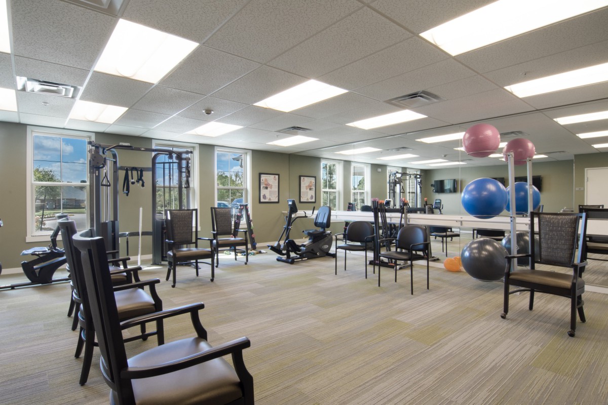 A well-lit gym with various fitness equipment and exercise balls.