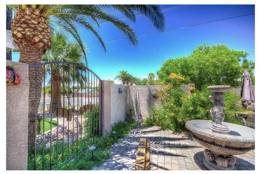 A sunny garden patio with palm trees and vibrant greenery.