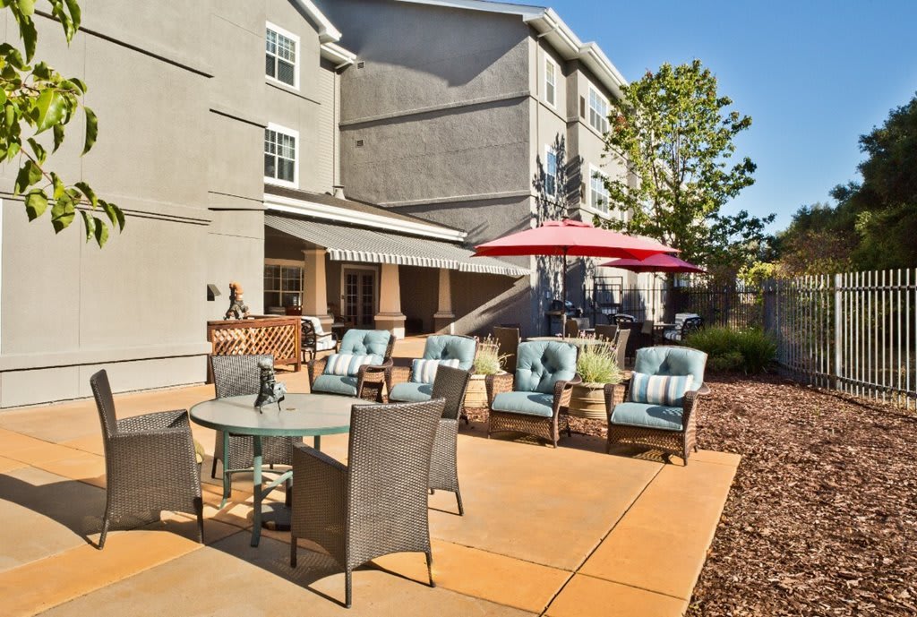 A spacious patio area with comfortable outdoor seating, umbrellas, and a view of the building's exterior on a sunny day.