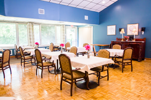 A cozy dining area with tables set for meals, adorned with flowers and bathed in natural light.