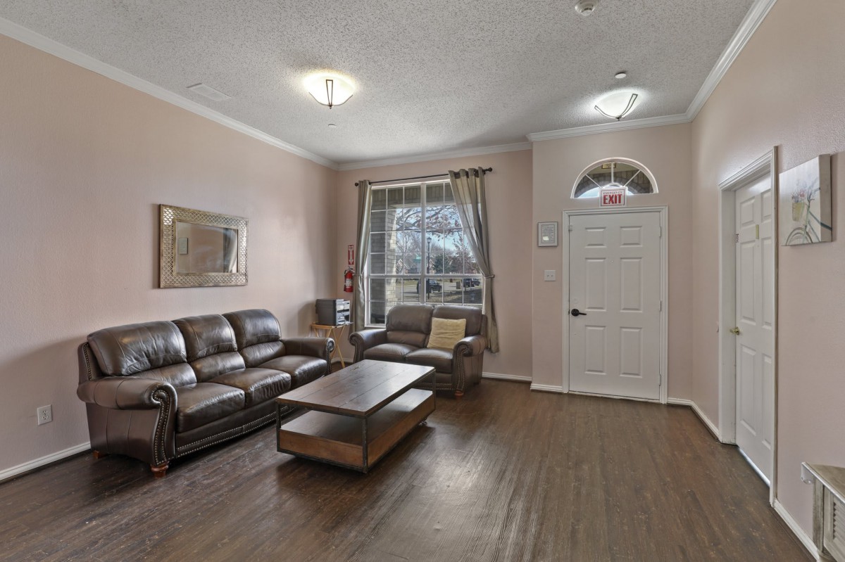 A cozy living room with a large sofa set, coffee table, and wooden flooring.