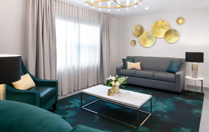 A stylish modern living room featuring a gray sofa, marble coffee table, elegant curtains, and decorative wall art with gold accents.