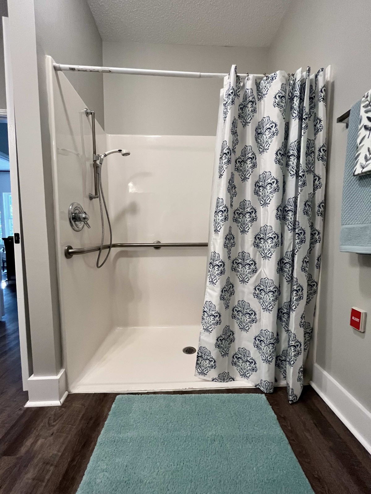 An accessible shower with grab bars and a patterned curtain.