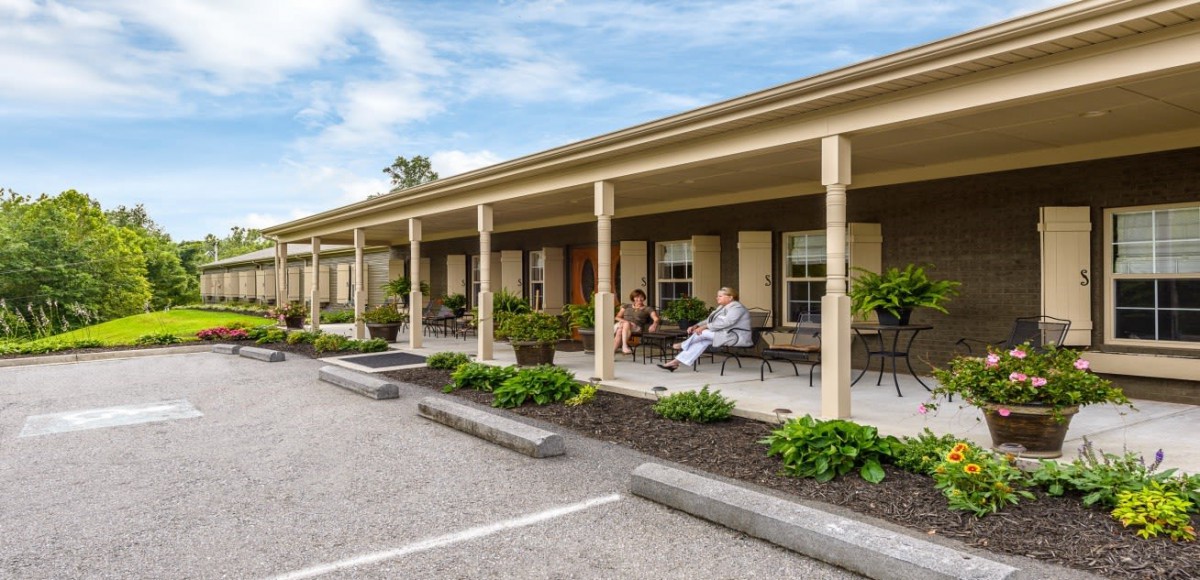 A view of a motel with a covered porch and outdoor seating area.