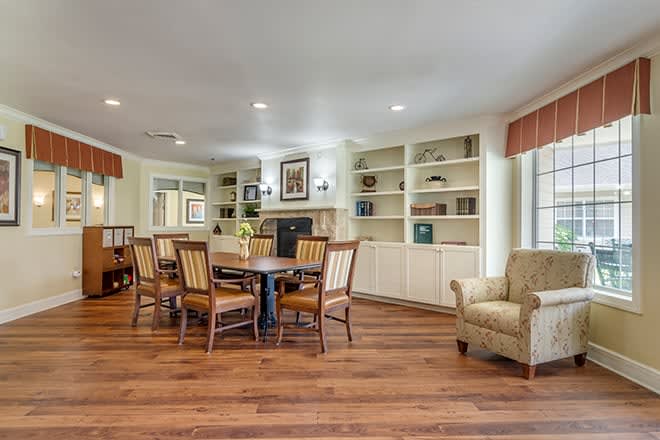 A cozy living and dining area with wood flooring, built-in bookshelves, and classic furniture.