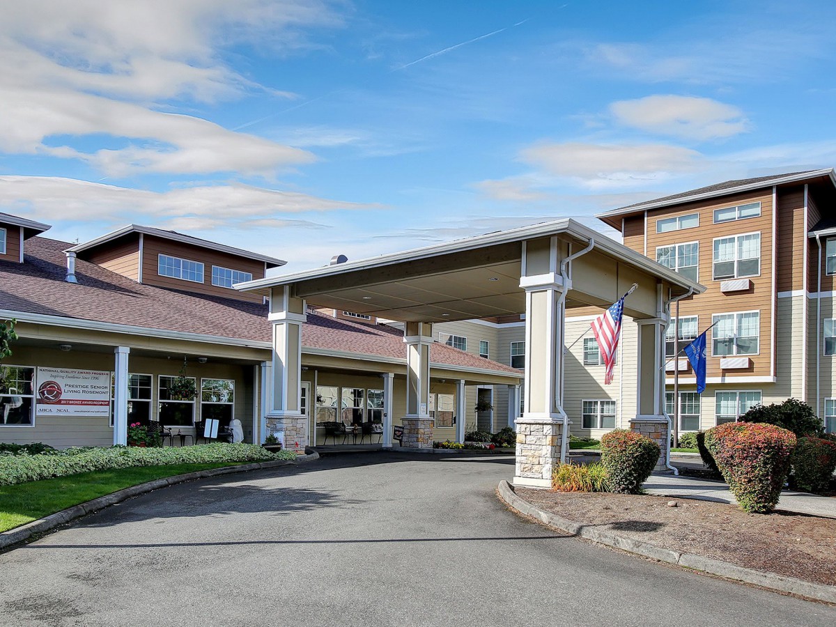 A building entrance with a covered driveway and visible landscaping.