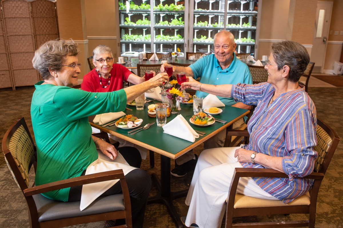 A group of seniors enjoying a meal and toasting at a restaurant.