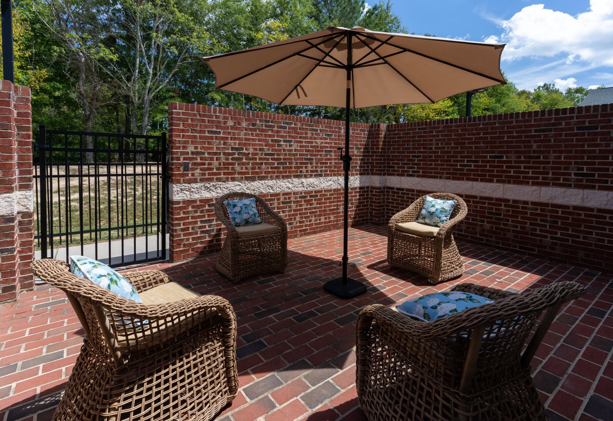 A peaceful outdoor patio setup featuring wicker chairs and a large umbrella, perfect for relaxation on a sunny day.