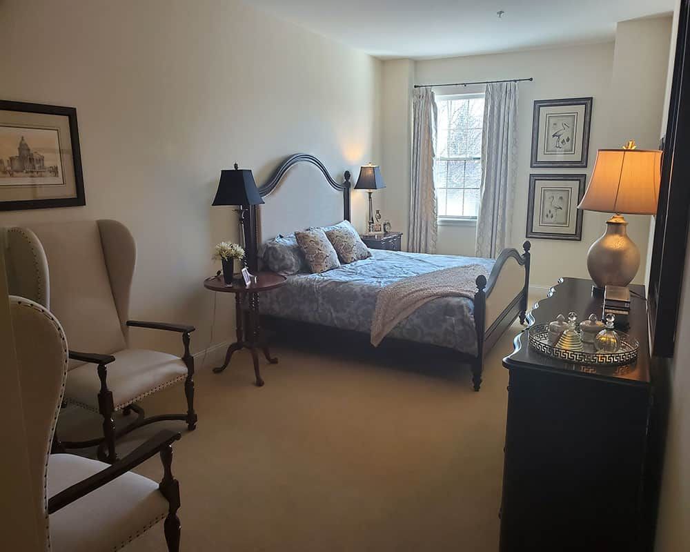 A cozy bedroom with a large window, elegant furniture, and soft lighting.