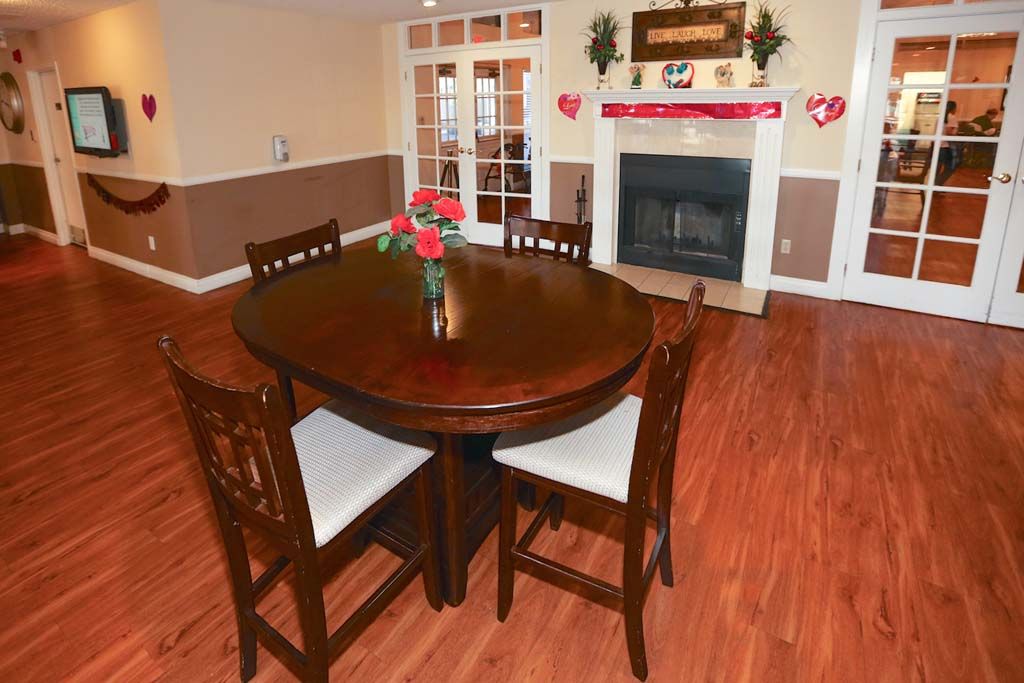 A cozy dining area with a round wooden table and chairs, adorned with Valentine's Day decorations, featuring a fireplace in the background.