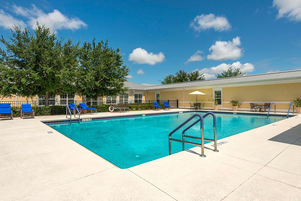 A clear, inviting outdoor swimming pool under a sunny blue sky.
