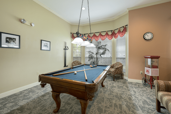 A cozy game room featuring a classic pool table under elegant lighting.