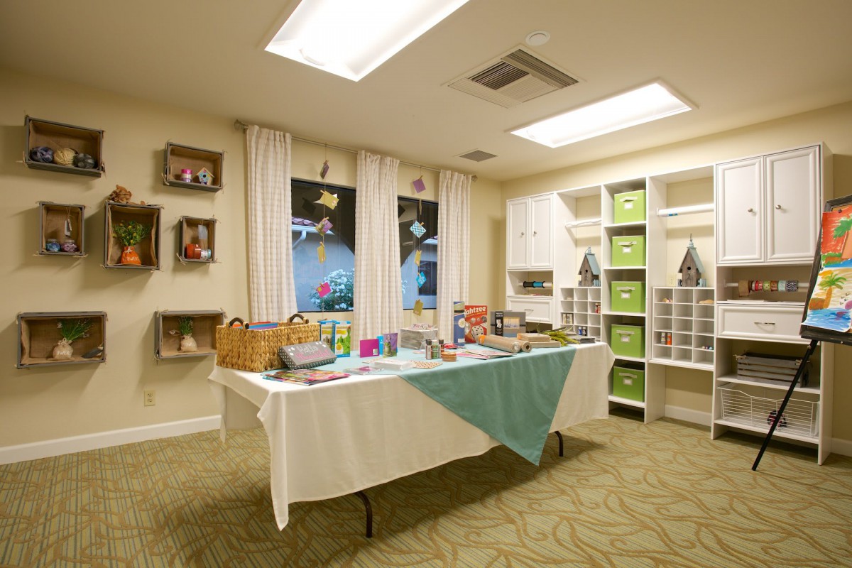 A well-lit room with a table set up for crafts and activities, surrounded by shelves and decorations.