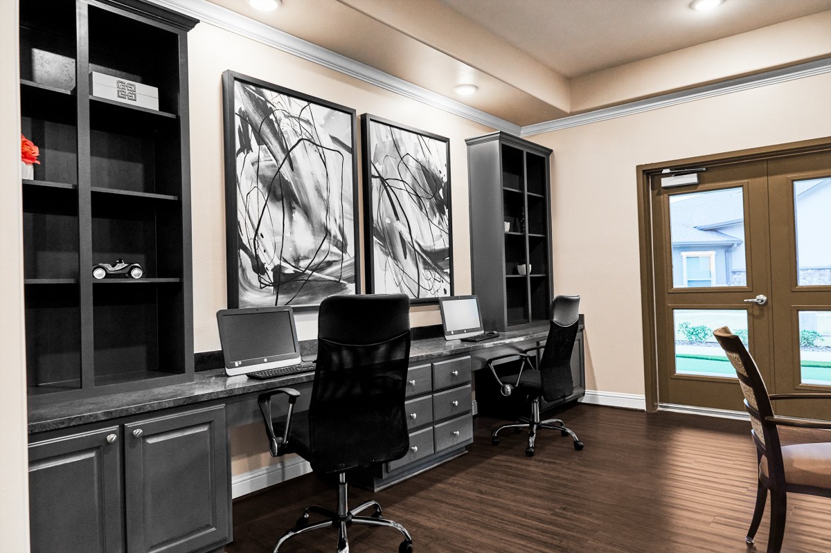 A modern home office setup with dual workstations and abstract artwork.
