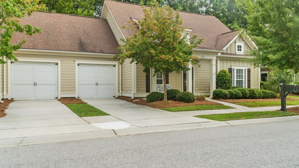 A suburban house with an attached garage and a tree in the front yard.