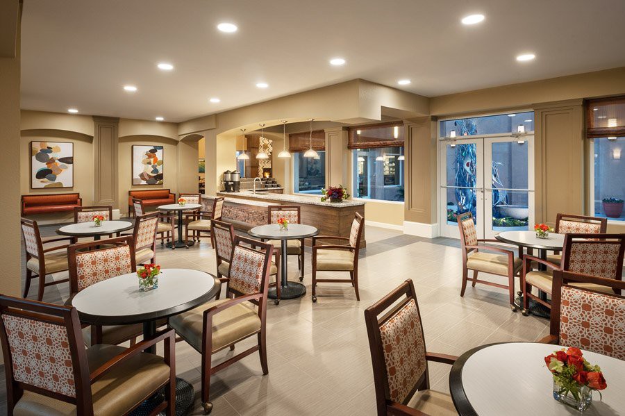 A cozy dining area with neatly arranged tables and chairs, illuminated by warm indoor lighting.