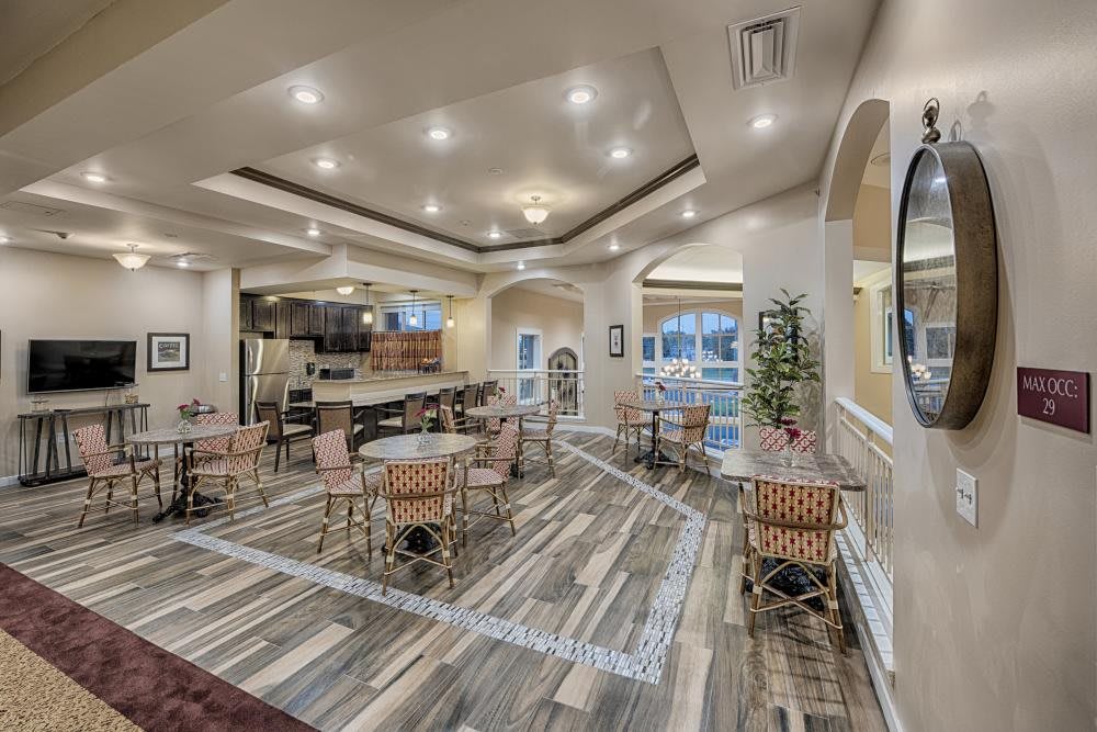A modern cafe interior with stylish decor, featuring multiple tables and chairs under elegant ceiling lights.