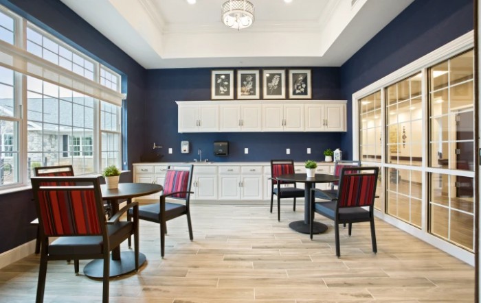 A modern kitchen and dining area with sleek furniture, wood flooring, and elegant light fixtures.
