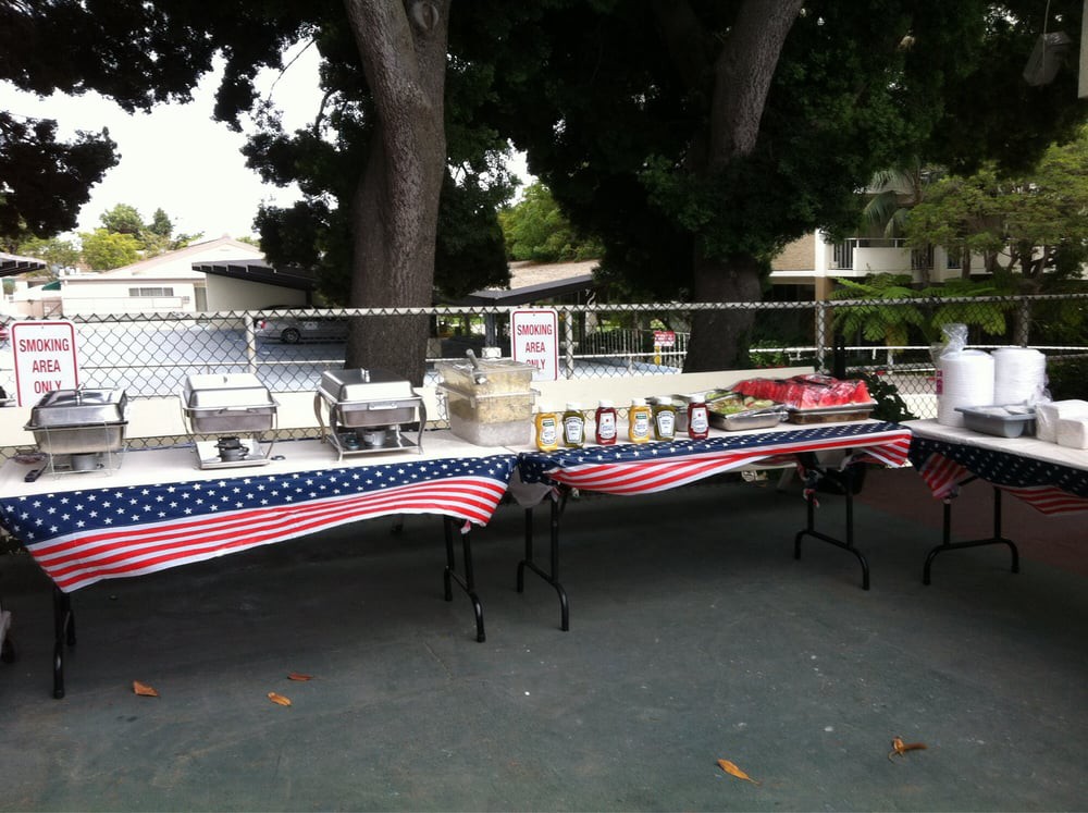 Outdoor buffet table setup with American flag tablecloths.