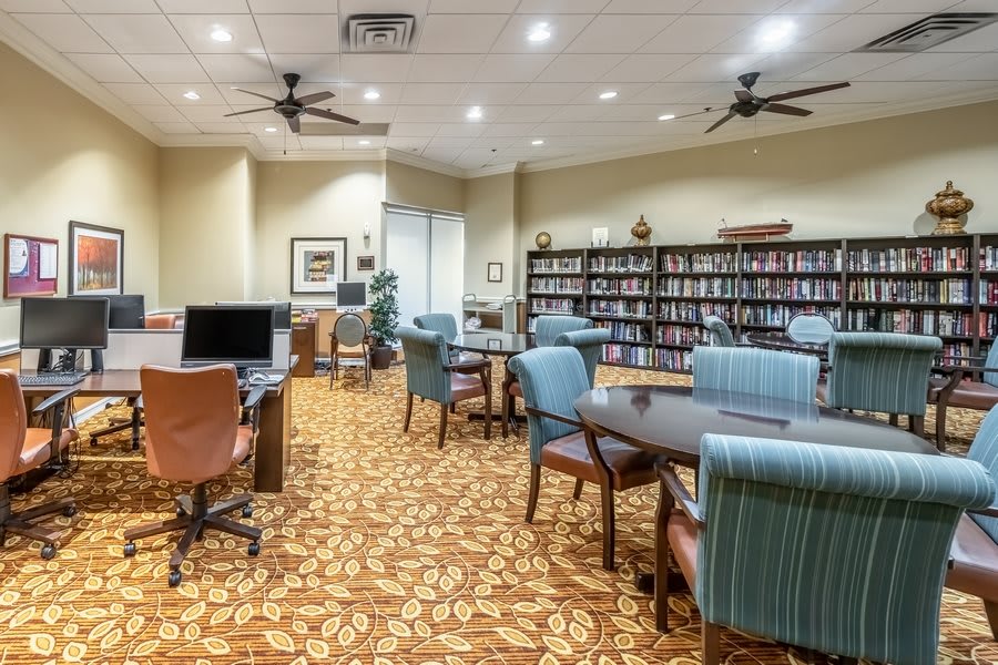 A quiet library room with computers, bookshelves, tables, and chairs.