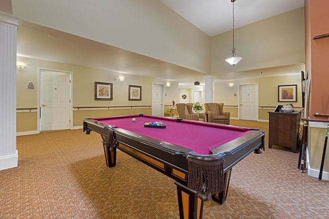 A well-furnished recreation room featuring a pool table with a magenta felt.
