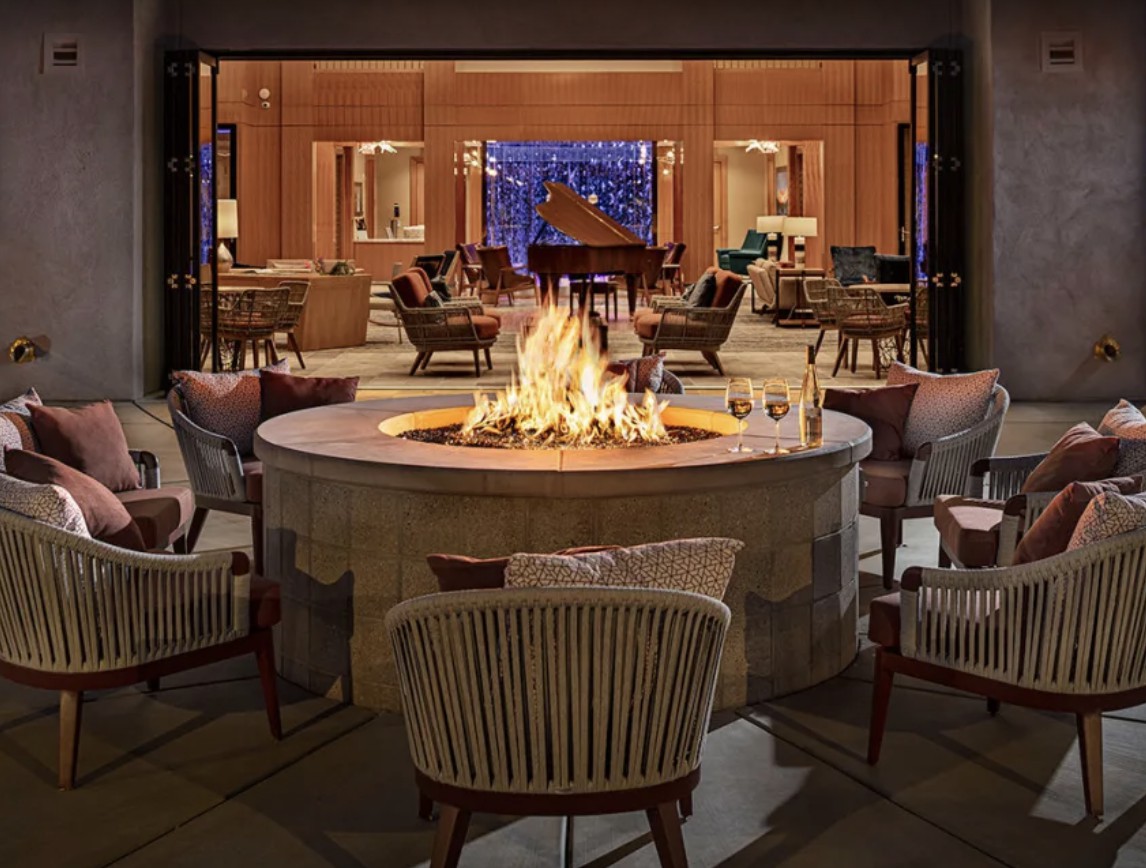 A stylish outdoor lounge area featuring a central fire pit surrounded by comfortable seating, perfect for a cozy evening gathering.