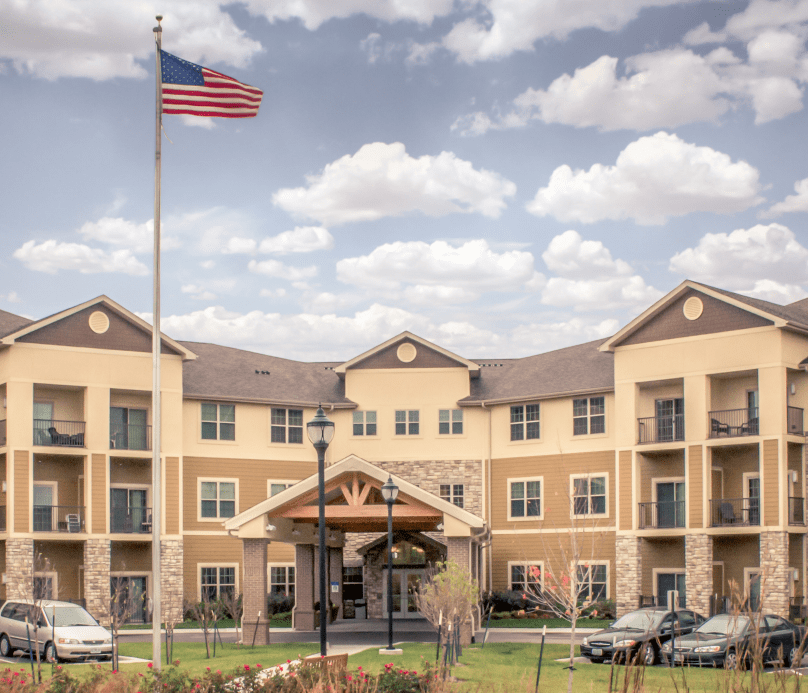 A large hotel building with an American flag flying in front, set against a partly cloudy sky.