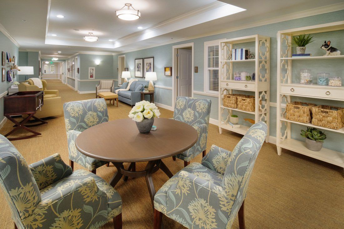 A cozy living space with a round table and patterned chairs, surrounded by bookshelves and elegant decor.