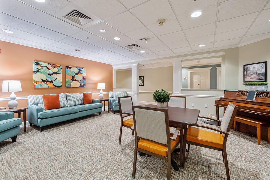 A cozy living area with a dining table and chairs, complemented by a sofa and decorative artwork on the walls.