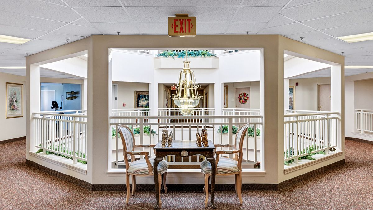 An elegant hotel lobby with a chandelier, seating area, and exit sign.