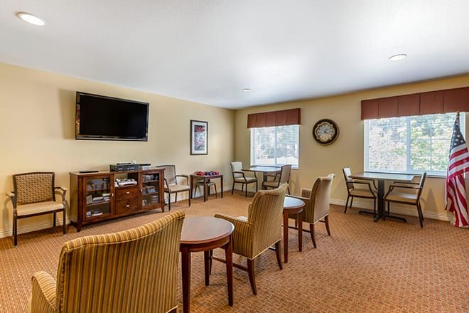 A cozy living room with chairs, tables, and a television.