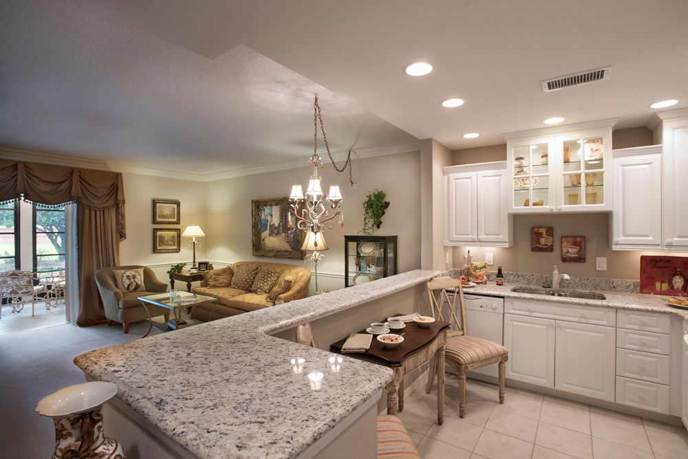A modern open-concept kitchen and living room with granite countertops and elegant lighting.