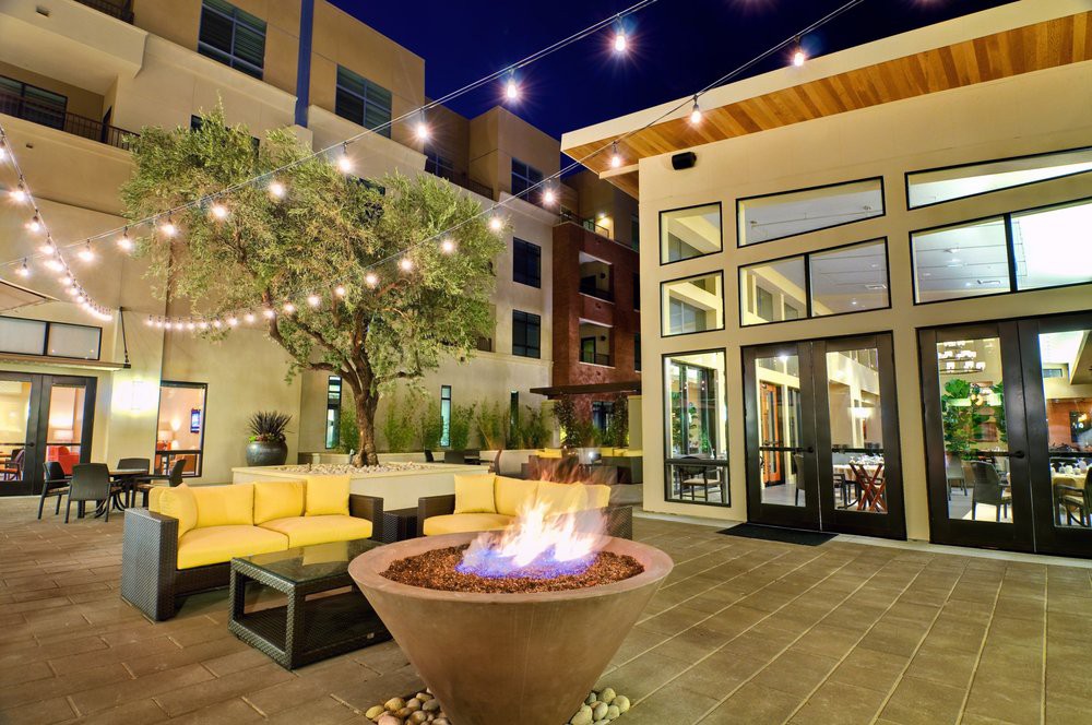 A cozy outdoor patio with a fire pit and string lights at night.