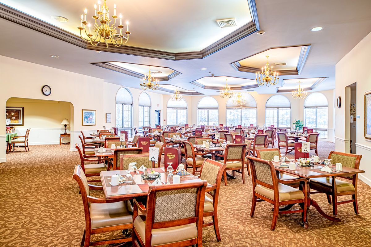 An elegant and spacious dining room with neatly arranged tables and chandeliers.