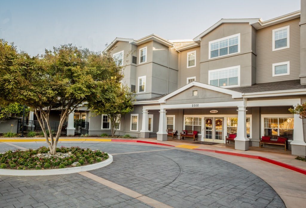 A multi-story residential building with a landscaped entrance and driveway.